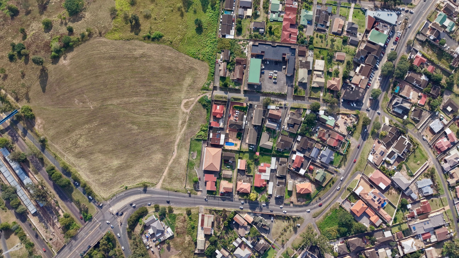 Aerial view of undeveloped green open land meeting the edge of a growing town - the kind of land-use boundary a conservation map documents.