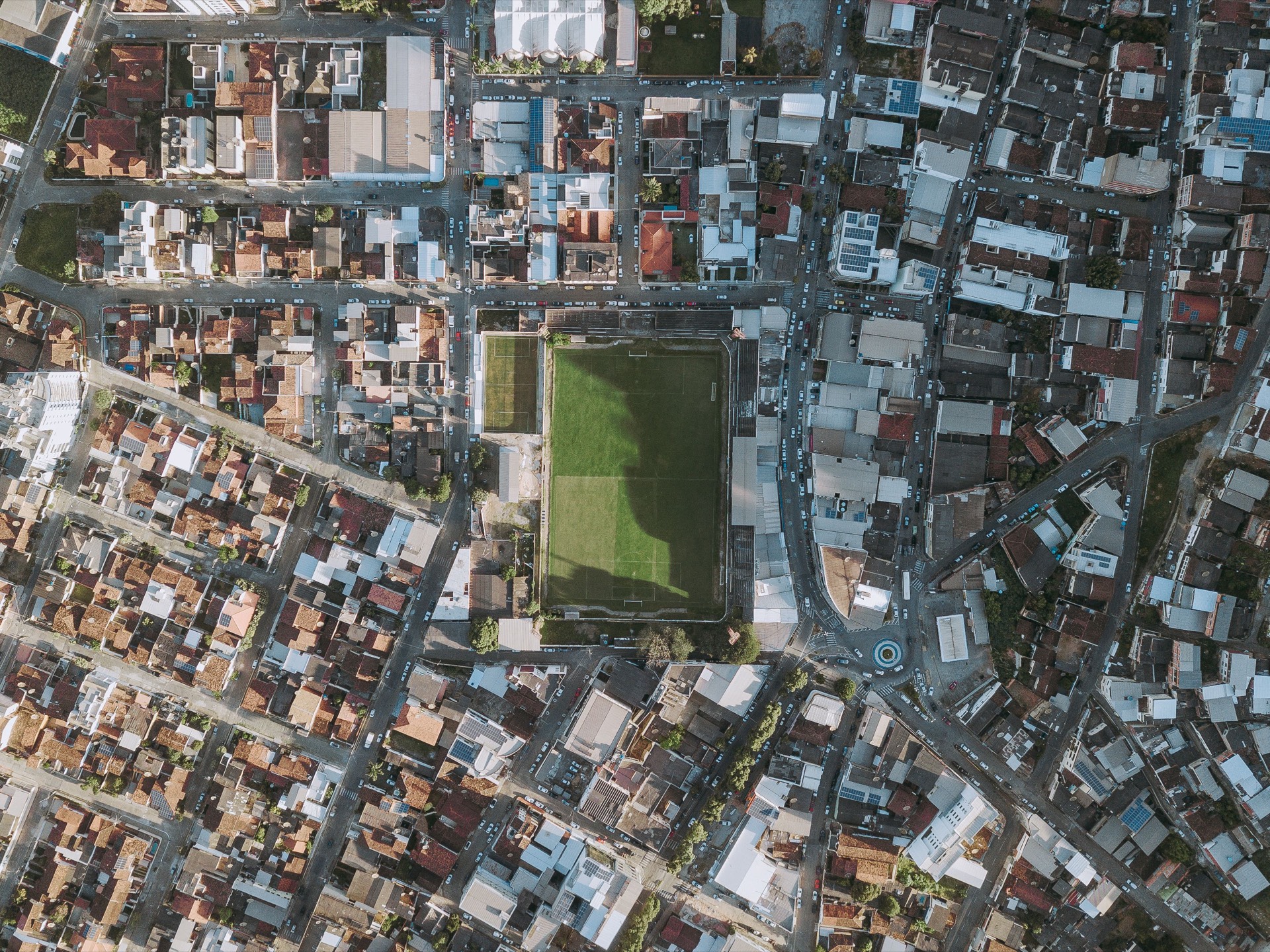 Overhead aerial map of a dense city grid with a green sports field at its center